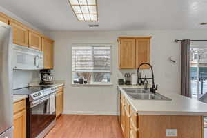 Kitchen with stainless steel appliances, a peninsula, light countertops, light brown cabinetry, and light wood-type flooring