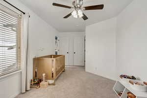 Bedroom with carpet flooring, multiple windows, and ceiling fan