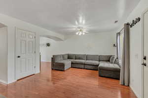 Living room featuring ceiling fan, light wood finished floors, and arched walkways
