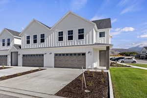 Modern farmhouse style home with board and batten siding, driveway, and roof with shingles