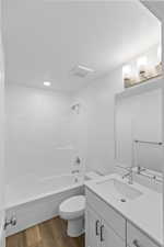 Bathroom with vanity, bathtub / shower combination, dark wood-style floors, and a textured ceiling