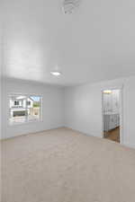 Unfurnished bedroom featuring light carpet, connected bathroom, and a textured ceiling