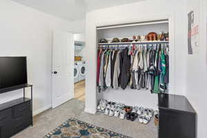 Bedroom featuring a closet, light carpet, and washing machine and clothes dryer