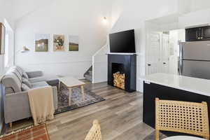 Living room featuring light wood-style floors, stairs, and high vaulted ceiling