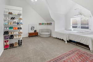 Carpeted bedroom featuring vaulted ceiling and baseboards