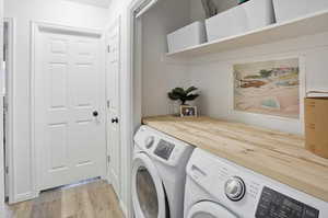 Laundry area featuring light wood finished floors and separate washer and dryer