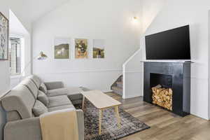 Living room featuring a fireplace, wood finished floors, lofted ceiling, and stairs