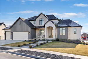 View of front of house with a front lawn, driveway, roof with shingles, and a garage