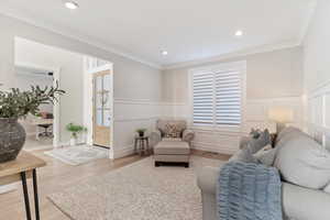 Sitting room with wood finished floors, crown molding, wainscoting, and recessed lighting