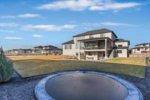 Rear view of property featuring stairway, a trampoline, a patio, a residential view, and a balcony