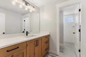 Full bath with a walk in shower, vanity, and light tile patterned floors