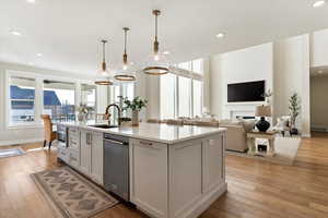 Kitchen featuring a center island with sink, light wood-style flooring, white cabinets, decorative light fixtures, and recessed lighting