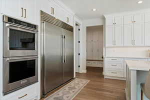 Kitchen with stainless steel appliances, white cabinetry, light wood finished floors, and recessed lighting