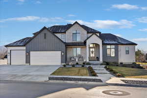 View of front of house with driveway, a front yard, a garage, and board and batten siding