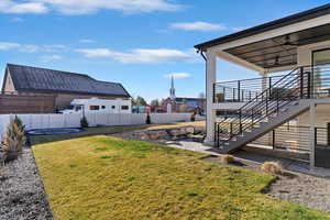 Fenced backyard with a ceiling fan, stairs, and a patio