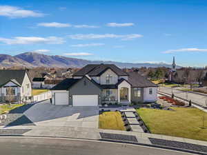 View of front of home featuring driveway, a mountain view, an attached garage, roof with shingles, and stone siding