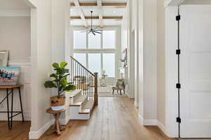 Hallway featuring light wood-type flooring, coffered ceiling, beam ceiling, and stairway