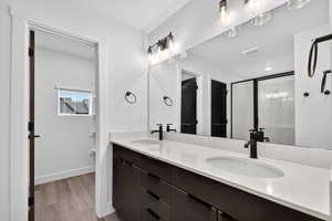 Bathroom featuring a shower stall, light wood-style floors, and double vanity