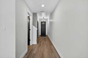 Corridor with light wood finished floors and a chandelier