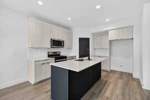 Kitchen featuring modern cabinets, light stone countertops, stainless steel appliances, light brown cabinetry, and light wood finished floors