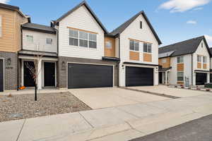 View of front facade featuring brick siding, concrete driveway, a garage, and a residential view