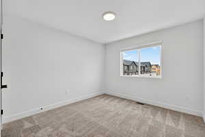 Empty room featuring light carpet and baseboards