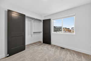 Unfurnished bedroom featuring a closet and light colored carpet