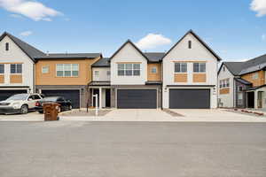 View of front of house featuring a residential view, brick siding, driveway, and an attached garage