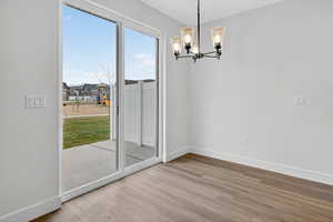 Unfurnished dining area with a chandelier and light wood-type flooring