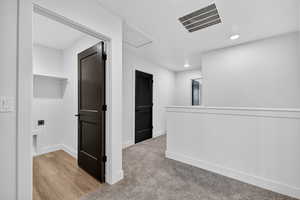 Corridor with recessed lighting, light wood-type flooring, and light colored carpet