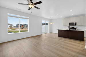 Kitchen featuring an island with sink, a chandelier, hanging light fixtures, light wood-style flooring, and recessed lighting