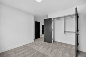 Unfurnished bedroom with light carpet and a closet