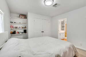 Bedroom with a closet, light carpet, and ensuite bath