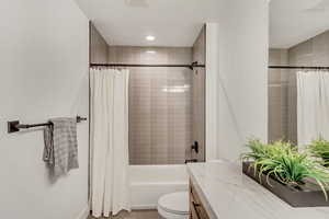Bathroom featuring shower / bath combination with curtain, vanity, and light tile patterned flooring