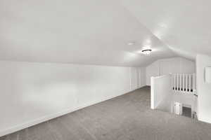 Bonus room with lofted ceiling, carpet flooring, and a textured ceiling