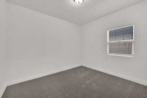 Unfurnished room featuring dark carpet and baseboards