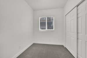 Unfurnished bedroom featuring dark carpet and a closet
