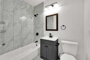 Bathroom featuring shower / bath combination, vanity, and a textured wall