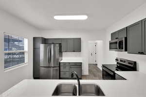 Kitchen featuring gray cabinetry, stainless steel appliances, and wood finished floors