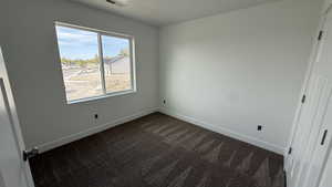 Unfurnished bedroom with baseboards and dark carpet