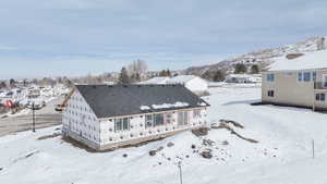 Snow covered rear of property featuring a mountain view
