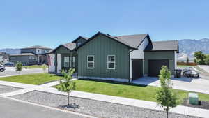 View of front of house featuring a mountain view, board and batten siding, a front yard, and concrete driveway