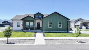 View of front of property with board and batten siding, a front lawn, covered porch, and roof with shingles