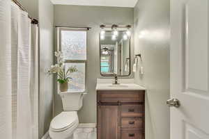Ensuite Bathroom 1 with vanity, curtained shower, light tile patterned floors, and a ceiling fan