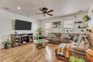 Living room with light wood-type flooring, a ceiling fan, and recessed lighting
