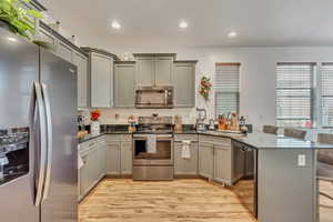 Kitchen featuring stainless steel appliances, a kitchen breakfast bar, gray cabinetry, and recessed lighting
