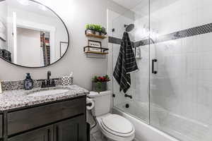 Bathroom with vanity and bath / shower combo with glass door