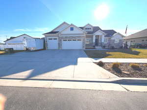 Craftsman-style house featuring board and batten siding, concrete driveway, a garage, stone siding, and a front lawn