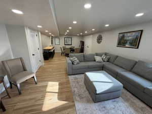 Living room with light wood-style flooring, recessed lighting, and a textured ceiling