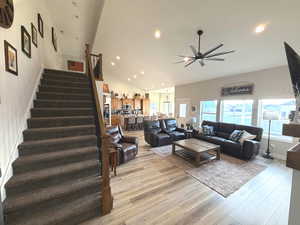 Living room featuring stairway, light wood-type flooring, recessed lighting, lofted ceiling, and ceiling fan